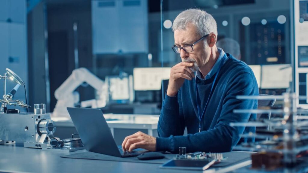 Picture of man in front of laptop in an electronics manufacturing site