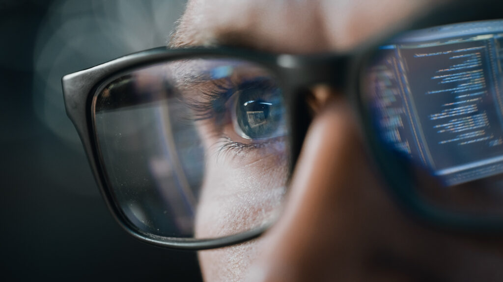 Close-up Portrait of Test Engineer Working on Computer, Line of Code Reflecting in Glasses